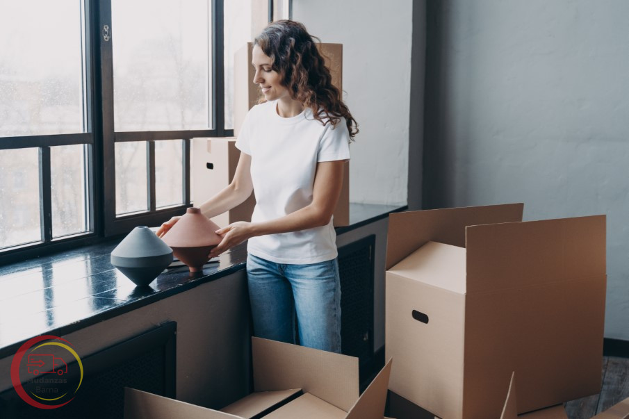 chica feliz desempacando una caja de carton con cosas para limpiar su nueva casa